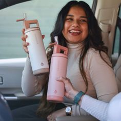 a woman sitting in the back seat of a car holding two water bottles