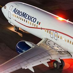 an aeromexico airplane sitting on the tarmac at night with its lights on