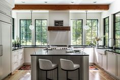 a kitchen with two stools next to an island in the middle of the room