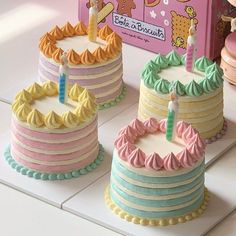 three birthday cakes sitting on top of a table next to a pink and blue box