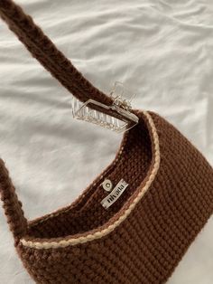 a crocheted brown purse sitting on top of a white sheet