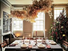 a dining room table is set with place settings for four people and the centerpieces are hanging from the ceiling