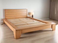 a bed with wooden slats and headboard in a white room next to a window