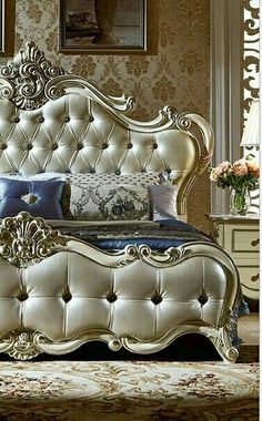 an ornate bed with blue and white pillows in a fancy bedroom setting on a carpeted floor