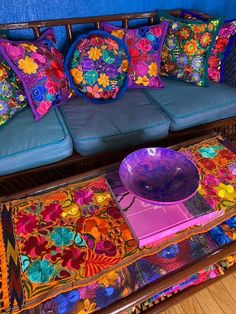 a couch covered in colorful pillows next to a table