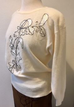 "White Lambswool Angora Pullover Sweater with Beaded Embroidered Leaf Design, by Renee Tener for Jeanne Pierre Size Medium This sweater is almost perfect except for 1 small mend job (pic no. 8) Features are a 3\" sock bottom along with end of sleeves, shoulder pads that can be removed and a beautiful beaded embroidered design on the front. The tube beads look like a dark silver and they edge the design that is filled with shimmery white embroidery stitches and also silver stud like beads. Really Embellished Crew Neck Sweater For Fall, Elegant White Embroidered Sweater, Elegant Floral Embroidered Tops For Winter, Vintage Embroidered Winter Top, Elegant Embroidered Winter Sweater, Elegant Embroidered Winter Tops, Spring Wool Embroidered Sweater, Spring Wool Sweater With Embroidery, Spring Embroidered Wool Sweater