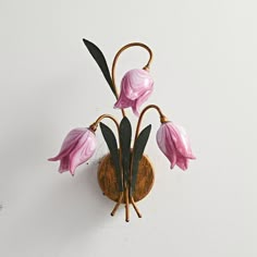 a pink flower sitting on top of a wooden wall mounted vase next to a white wall