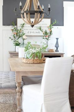 a dining room table with white chairs and a chandelier hanging from the ceiling