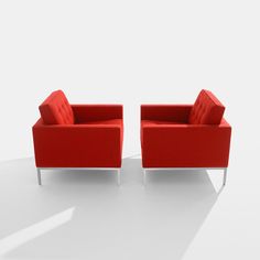 two red chairs sitting next to each other on a white floor