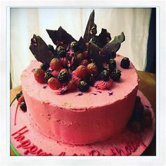 a pink cake with berries and leaves on top