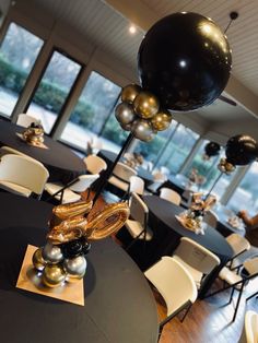 a room filled with tables covered in black and gold balloons