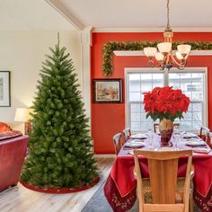 a dining room decorated for christmas with red and green decorations on the table, chairs, and tree