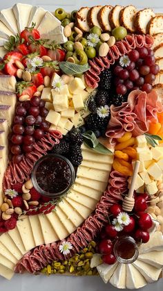 a platter with cheese, fruit and crackers arranged in the shape of a fish