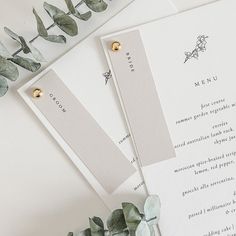 the wedding stationery is laid out on top of each other, with greenery