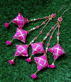 pink and gold ornaments are laying in the grass on top of some green grass with beads