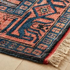 a blue and red rug with fringes on the floor