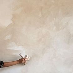 a woman is painting the wall with rollers and paintbrushes in her hand