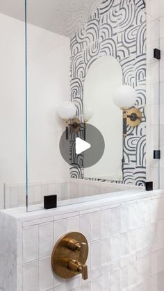 a bathroom with white tile and gold faucet in the corner, along with a large mirror on the wall