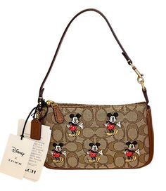 New with Tags Comes with Coach gift box, Tissue paper and sticker Bag wasn’t displayed and comes in original manufacturer packaging This Coach X Disney Nolita 19 wristlet, model CN507, is a stylish accessory that will add a touch of fun to any outfit. The exterior features a brass/khaki/redwood multi-colored signature jacquard pattern, with a cute Mickey Mouse character accent. The wristlet has a zip closure and a convenient wrist strap drop of 6.25". Inside, there are credit card slots for adde Coach Nolita 19, Coach X Disney, Nolita 19, Mickey Mouse Characters, Mouse Character, Cute Mickey Mouse, Dream Bag, Disney World Outfits, Tan Shoulder Bag