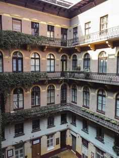 an apartment building with lots of windows and plants growing on the balconies above