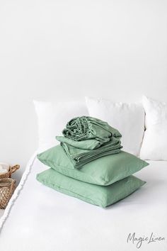 pillows and blankets stacked on top of each other on a bed with white linens