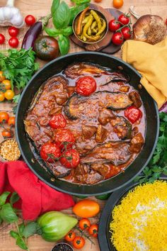 a pan filled with meat and vegetables on top of a wooden table next to other foods