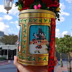 a person holding up a decorated cup in front of a building with decorations on it