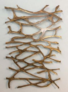 a metal sculpture made out of branches on a white wall