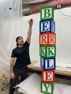 a man in black shirt standing next to blocks that spell out be r r k y