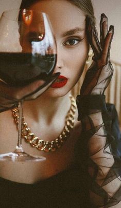 a woman holding a glass of wine in front of her face