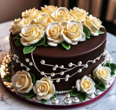 there is a chocolate cake with white roses on top and pearls around the edges,