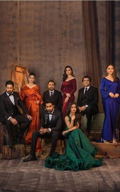 a group of people sitting next to each other in front of a wooden wall wearing suits and ties