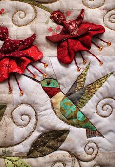 two birds with red and green wings on a quilt