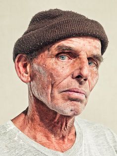 an old man with wrinkles and a hat on his head is looking at the camera