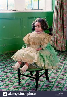 an old doll sitting on a chair in a room with green walls and flooring