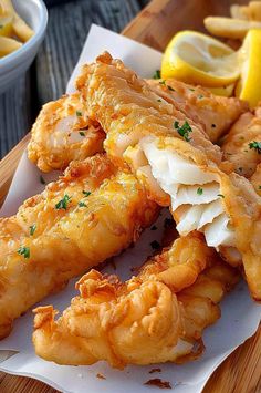 some food is laying out on a wooden table next to lemon wedges and fries