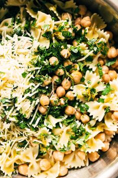 a bowl filled with pasta, spinach and chickpeas covered in parmesan cheese