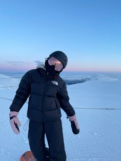 a person on a snowboard in the snow wearing a black jacket and goggles