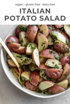 a white bowl filled with potatoes and parsley on top of a table next to a spoon