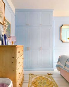 a bedroom with blue painted walls and white flooring has a rug on the floor