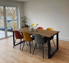 a dining room table with chairs and vases on top of it in front of a sliding glass door