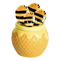 three bees sitting on top of a yellow honeycomb jar filled with honeybees