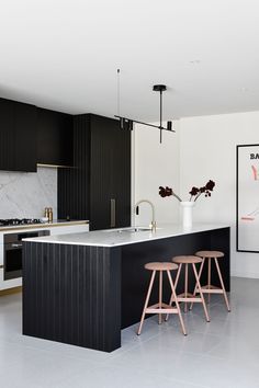 a black and white kitchen with stools next to an island counter top in the middle