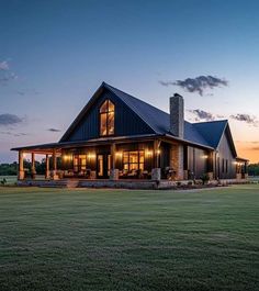 a large house sitting in the middle of a field at night with lights on it's windows