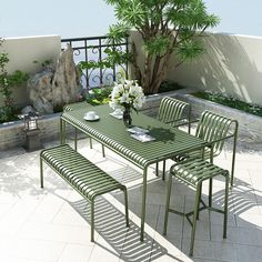 a table and chairs on a patio near a tree with potted plants in the background