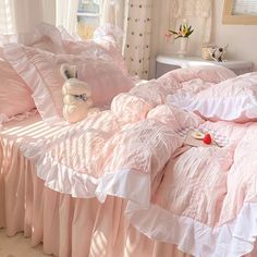 a pink bed with ruffled sheets and pillows