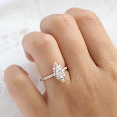 a woman's hand with a diamond ring on top of her finger and white lace in the background