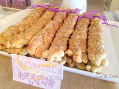 some bread sticks are on a white plate and purple ribbon is tied around the edges