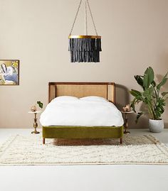 a bed sitting on top of a white rug next to a green chair and potted plant