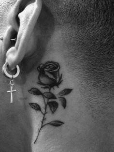 a woman's neck with a cross and rose tattoo on it